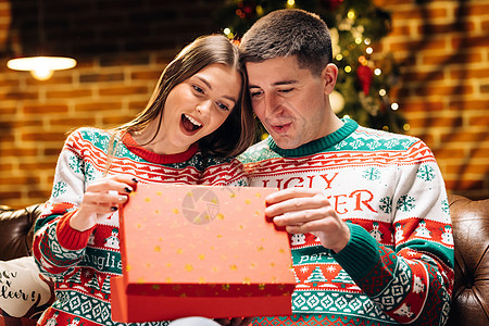 一对浪漫情侣的画像 晚上在装饰精美的圣诞树附近打开礼物盒 快乐的男人正在给他心爱的女人做圣诞礼物 假期 浪漫 惊喜的概念 展示 图片