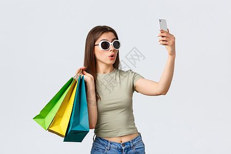 购物中心 生活方式 旅游和时尚概念 戴着太阳镜 带着购物袋自拍 在最喜欢的商店买东西的快乐迷人女游客 脸 裙子图片