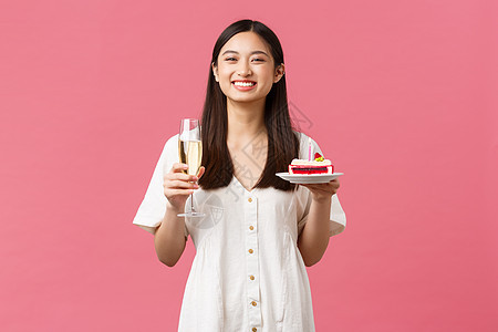 庆祝活动 派对假期和有趣的概念 快乐的亚洲女人庆祝生日 享受美味的生日蛋糕和喝香槟 对着镜头微笑 欢快的粉红色背景 女性 美丽的图片