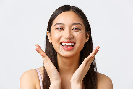 美容 时尚和化妆产品广告的概念 美丽的亚洲女孩在脸上展示护肤品的特写 对化妆很满意 微笑着乐观图片