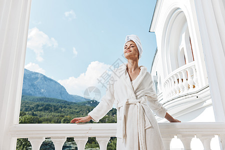 身着白袍的美女 在阳台上 在绿色自然山观上图片