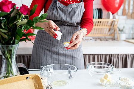 穿着红裙子和灰色围裙的女人 在厨房做情人节烹饪图片