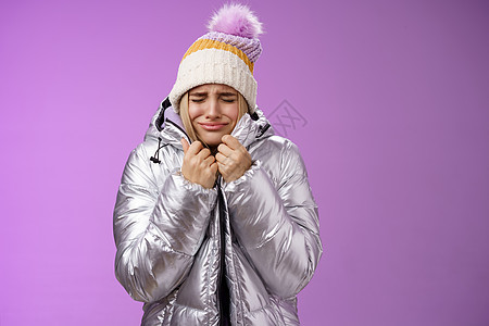 不开心的抽泣呜呜着可爱的金发女孩拉紧夹克紧身闭上眼睛哭着冻僵站在多雪的冬季度假胜地摇晃低温 紫色背景痛苦不适 寒冷的 吃惊图片