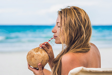 年轻女子在海滩的上喝椰子牛奶 假期 太阳图片
