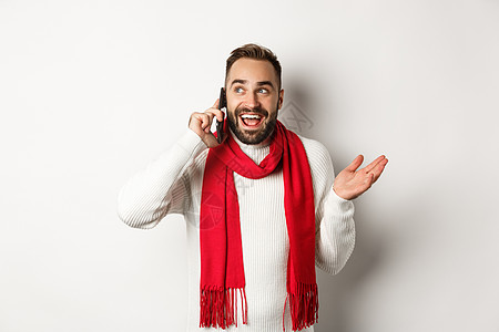 留着胡子的快乐男人在电话里祝圣诞快乐 打电话给别人说话 穿着带红围巾 白色背景的毛衣 幸福 脸背景图片