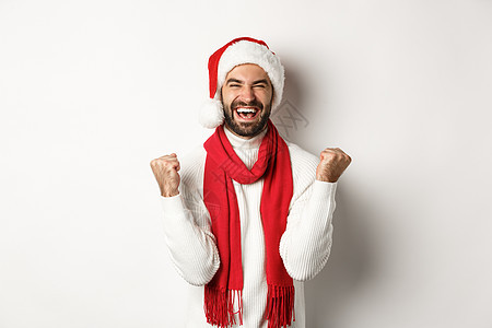 圣诞假期 男子获胜者庆祝和胜利 举起双手欢欣鼓舞 实现目标 戴着圣诞帽和红围巾 白色背景 男人 大胡子图片
