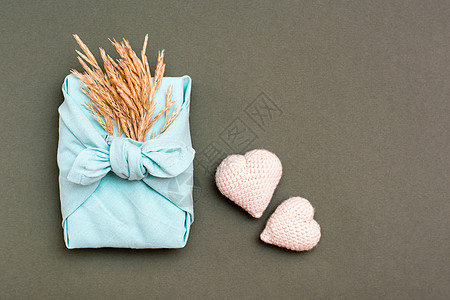 赠送生态友好的furoshiki礼物 上面有干草耳朵和绿色背景上两颗编织的心图片
