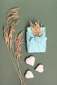 生态友好情人节当天的礼物furoshiki 编织的心和绿背景上的干草耳朵 垂直视图图片