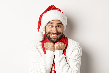 新年晚会和冬季假期概念 圣诞老人帽子的帅哥对圣诞节感到兴奋 在白色背景下欢乐地站立起来图片