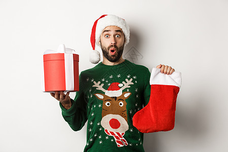Xmas和冬季假期概念 享受着圣诞袜和礼物盒 庆祝新年 站在白底的兴奋男子 站立在白底 毛衣 庆典图片