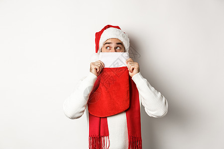 冬季假期和购物概念 圣诞老人帽子中的愉快的caucasian男子躲在圣诞袜后 带着礼物站在白色背景上 庆典 短袜图片
