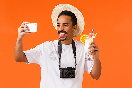 有魅力 热情 风趣的年轻非洲裔美国人微笑 欢呼 喝酒 自拍 拍照 拿着相机 暑假旅游图片