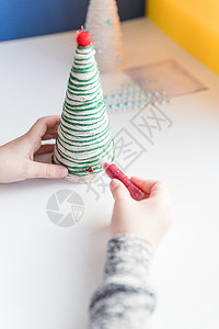 孩子正在展示圣诞树装饰 制作创意手工圣诞树 儿童 DIY 概念 制作圣诞玩具装饰 用水钻装饰玩具 生态友好的圣诞树概念 复制空间图片