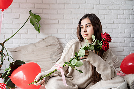 年轻美女坐在床上 庆祝情人节 盛着红玫瑰的晚礼日 礼物 卧室图片
