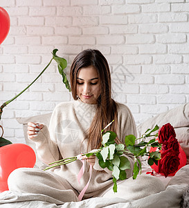 年轻美女坐在床上 庆祝情人节 盛着红玫瑰的晚礼日 心 女性图片