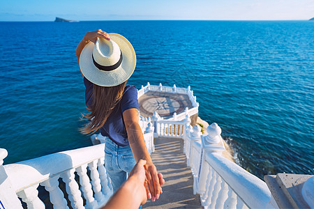 戴帽子的无端观光女游客将她的男朋友带往海景 请跟我来西班牙贝尼多姆图片