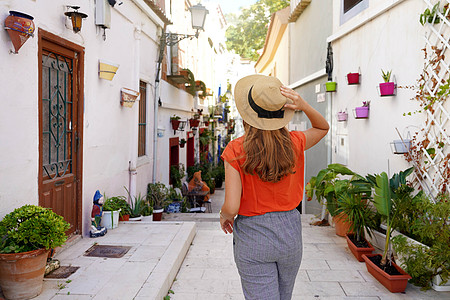 旅游女游客参观了西班牙的阿利坎特圣克鲁斯 Santa Cruz 街坊;旅游女游客探索欧洲城市 并拥有典型的地中海建筑和装饰图片