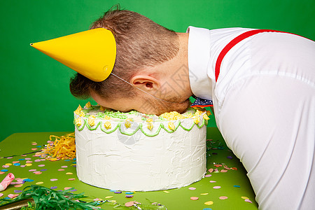 在生日蛋糕里 长着脸躺着的有趣男人 绿色背景 面包店图片