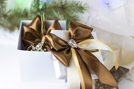 一份圣诞礼物 在浅色背景上用冷杉树枝装饰着美丽的蝴蝶结 礼物 喜悦 惊喜 选择性的焦点 圣诞节和新年的概念 弓 庆典图片