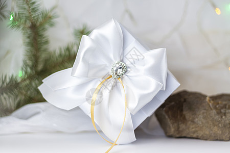 一份圣诞礼物 在浅色背景上用冷杉树枝装饰着美丽的蝴蝶结 礼物 喜悦 惊喜 选择性的焦点 圣诞节和新年的概念 药片 盒子图片