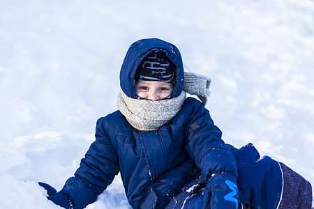 在阳光明媚的冬日 一个微笑快乐的孩子躺在雪堆里 下了很多雪 而且非常结霜 活跃的冬季户外游戏 孩子们 喀尔巴阡山脉图片