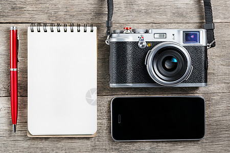 古典相机 上面有空白的笔记本页和灰色木头上的红色钢笔 旧桌子上有电话 桌面 工作图片