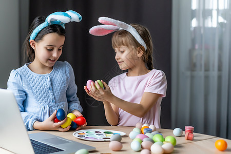 两个长着兔耳朵的可爱小女孩正在画复活节彩蛋 孩子们正在为春假做准备 复活节的心情 孩子们正在画彩蛋 艺术家 美丽的图片