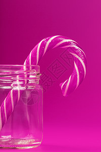 一个棒棒糖甘蔗 在玻璃罐里 粉红色背景图片