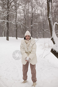 两个女孩在冬天的雪中打雪球 穿着温暖的冬衣 森林 乐趣图片
