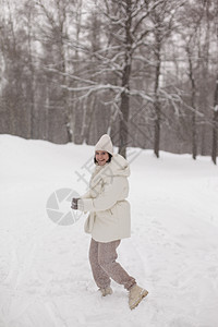 两个女孩在冬天的雪中打雪球 穿着温暖的冬衣 衣服 微笑图片