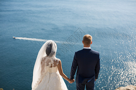 新娘和新郎在悬崖对海上牵手图片