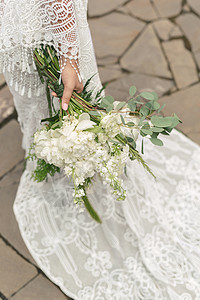 新娘在婚纱列车背景的新娘手中 用白色的花束子放在彩礼服上 庆典 仪式图片