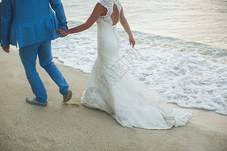 美丽的华丽新娘和时尚的新郎手牵手 在大海的背景上 浪漫的 腿图片