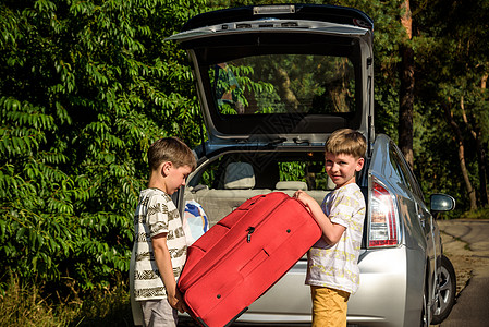 两个可爱的男孩拿着手提箱和父母一起去度假 两个孩子期待公路旅行或旅行 家庭自驾游 兄弟 坐着图片