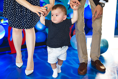 小男孩握着父母亲的手 试图迈出第一步 儿童与母亲和父亲同在 生日 笑图片