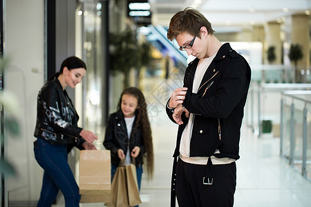 快乐的年轻家庭在购物中心买纸袋 用衣服去商店窗户 丈夫 男性图片
