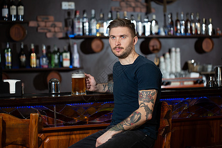 坐在酒吧柜台的年轻人 喝着一品脱轻啤酒 成人图片