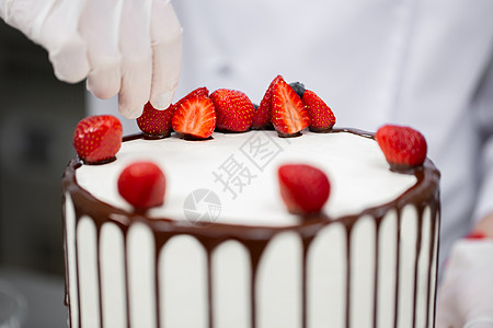 糕点厨师把蛋糕装饰成巧克力的草莓 庆典 周年纪念日图片