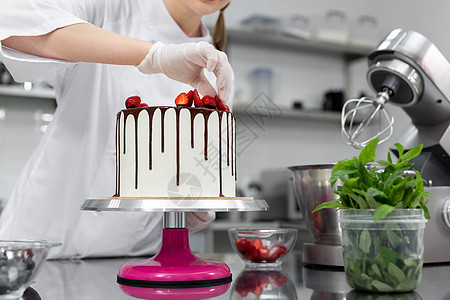 糕点厨师把蛋糕装饰成巧克力的草莓 面包店 桌子图片