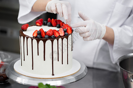 糕点厨师把蛋糕装饰成巧克力条纹的草莓和蓝莓 派对 面包店图片