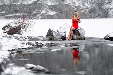 身着红裙子的年轻美女 在冬天雪冰冻湖边 寒冷的图片