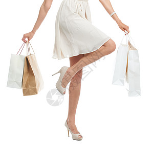 剪裁工作室拍到一个穿着鸡尾酒装的女人 在白色背景下拿着购物袋 她的脚步在跳着春 她跑去买东西图片