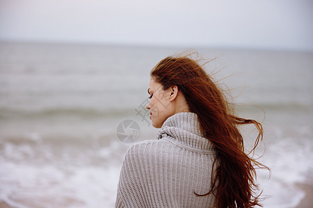 在海滩上长头发的漂亮美女 自然景观走在轻松的概念中 水 毛衣图片