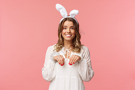 假期 春天和聚会的概念 可爱温柔 可爱的金发女孩模仿兔子的肖像 像爪子一样手牵手 戴着兔耳 微笑的相机 粉红色的背景 美丽的 时图片