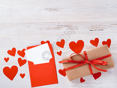 情人节的象征 — 牛皮纸牛皮纸礼盒 红丝带 信封 白色背景上有一张干净的空白纸 上面有很多红心 侧视图图片