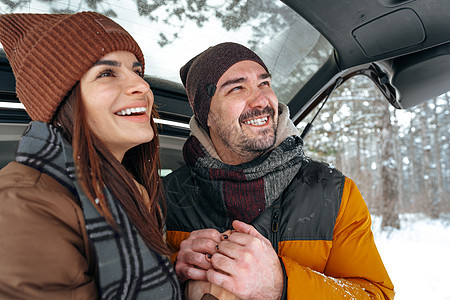 坐在冬季森林的汽车后备箱里可爱的一对笑着微笑的情侣 家庭 路图片