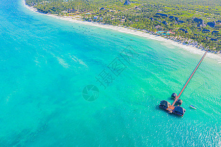 在坦桑尼亚桑给巴尔岛白沙滩海滩上用绿绿印度洋海浪冲洗棕榈头盖顶的斯图特小屋空中拍摄 树图片