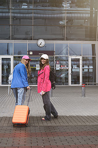 两个快乐的女孩在机场附近行走 带行李 空中旅行 暑假 女朋友 帽图片