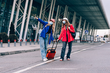 两个快乐的女孩在机场附近行走 带行李 空中旅行 暑假 爱 旅游图片