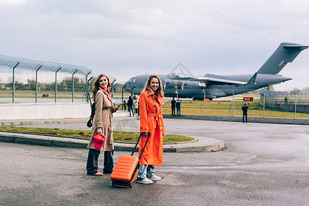 两个快乐的女孩在机场附近行走 带行李 空中旅行 暑假 头发 时尚图片